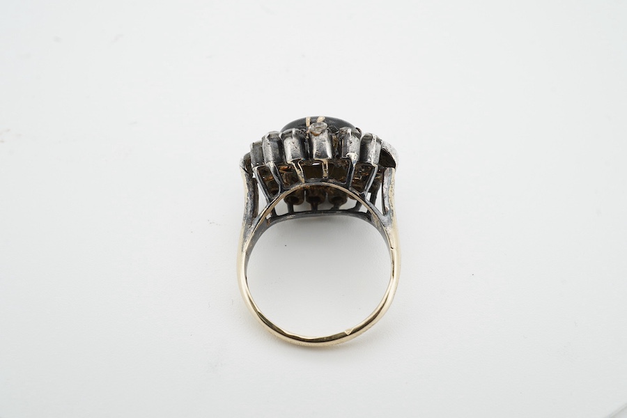 An Indian? yellow and white metal (shank stamped 18k), greyish star sapphire and simulated diamond cluster set dress ring, size O, gross weight 8.2 grams. Condition - poor (stone missing).